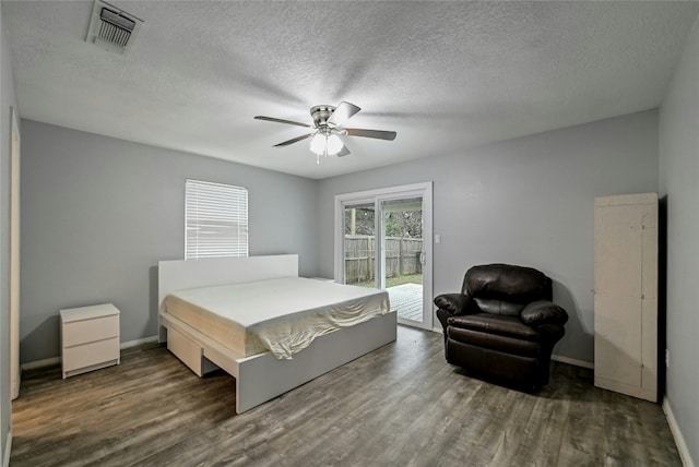 bedroom featuring dark hardwood / wood-style flooring, a textured ceiling, access to exterior, and ceiling fan