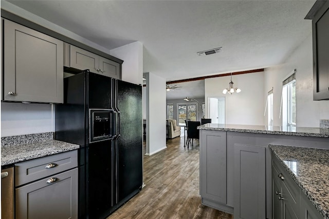 kitchen with dark wood-type flooring, black refrigerator with ice dispenser, stone counters, and gray cabinets