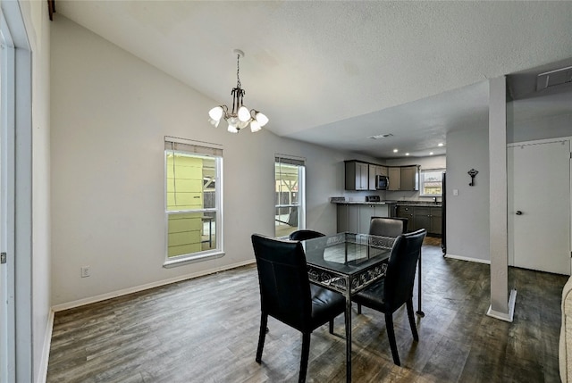 dining room featuring vaulted ceiling, dark wood-type flooring, a wealth of natural light, and a notable chandelier