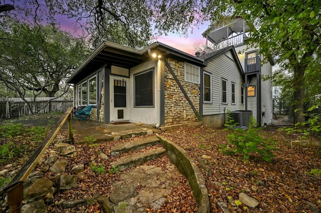 property exterior at dusk with a patio, a balcony, and central AC