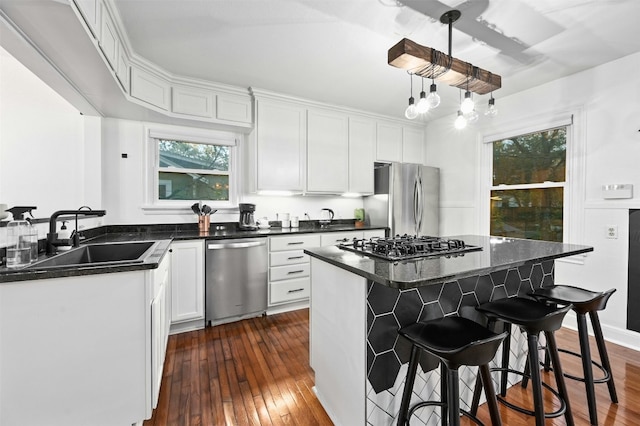 kitchen featuring dark hardwood / wood-style floors, decorative light fixtures, sink, white cabinets, and stainless steel appliances