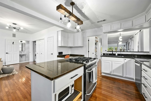 kitchen featuring white cabinetry, stainless steel appliances, dark hardwood / wood-style floors, and dark stone countertops