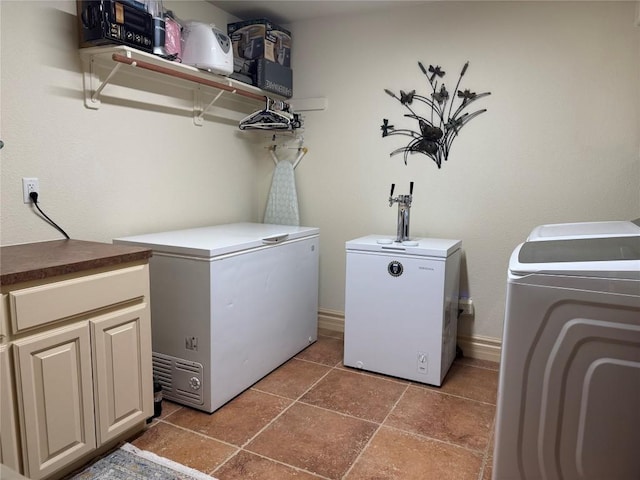 clothes washing area with dark tile patterned flooring, washer and clothes dryer, and cabinets