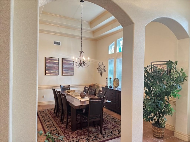 dining room featuring crown molding, a tray ceiling, a chandelier, and tile patterned flooring