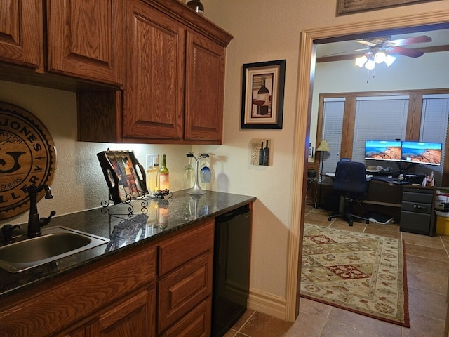 kitchen featuring ceiling fan, sink, refrigerator, and dark stone counters