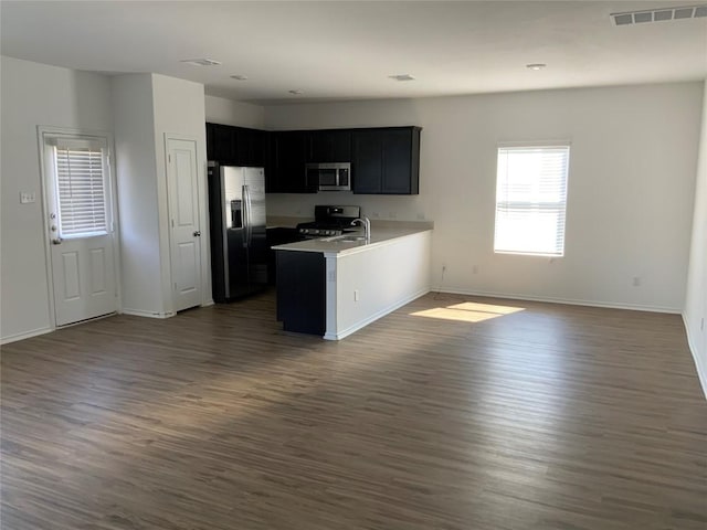 kitchen featuring sink, dark wood-type flooring, stainless steel appliances, and kitchen peninsula