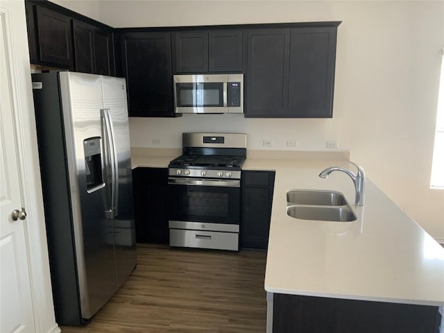 kitchen with appliances with stainless steel finishes, dark hardwood / wood-style floors, kitchen peninsula, and sink