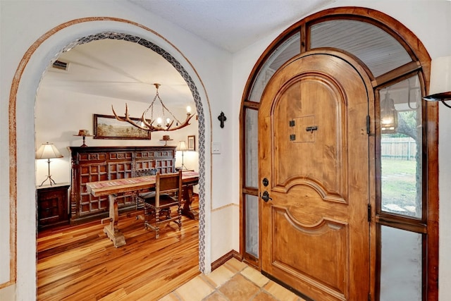 entryway featuring light wood-type flooring and a notable chandelier