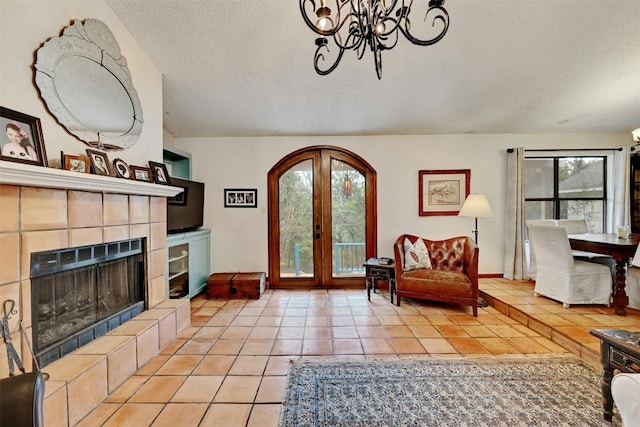 107 S Cuernavaca Dr, Austin, TX 78733 - living area featuring light tile patterned flooring, a chandelier, a textured ceiling, french doors, and a tiled fireplace