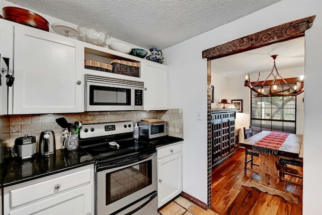 kitchen featuring an inviting chandelier, backsplash, stainless steel appliances, a textured ceiling, and white cabinets