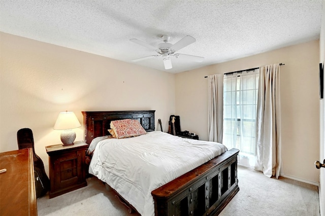 bedroom featuring light colored carpet, ceiling fan, and a textured ceiling