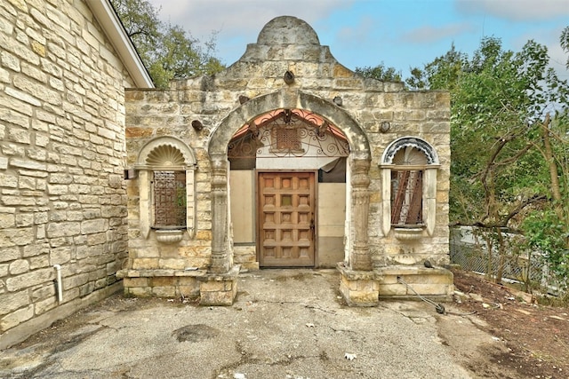 exterior space featuring stone siding and fence