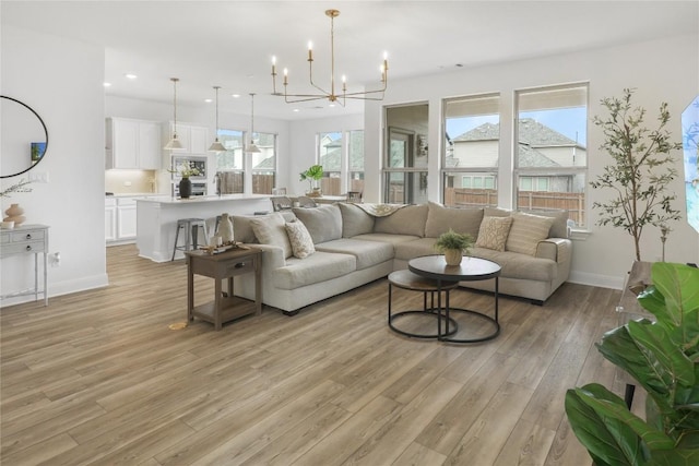 living room featuring a notable chandelier, light hardwood / wood-style floors, and a healthy amount of sunlight