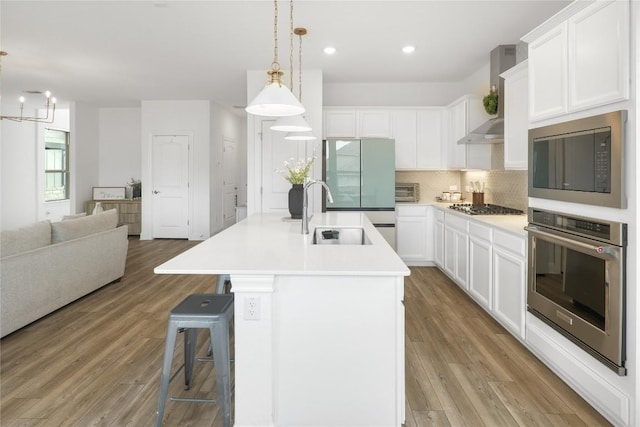 821 Olinda Way, Liberty Hill, TX 78642 - kitchen featuring stainless steel appliances, wall chimney exhaust hood, tasteful backsplash, light wood-style flooring, and recessed lighting