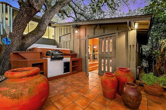 patio terrace at dusk featuring exterior kitchen and area for grilling