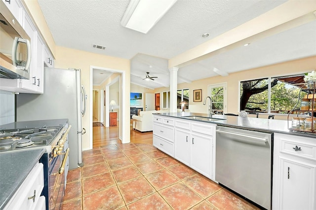 kitchen featuring sink, white cabinetry, light tile patterned floors, stainless steel appliances, and decorative columns