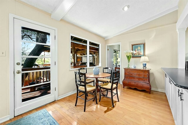 dining space featuring lofted ceiling with beams, a textured ceiling, and light wood-type flooring