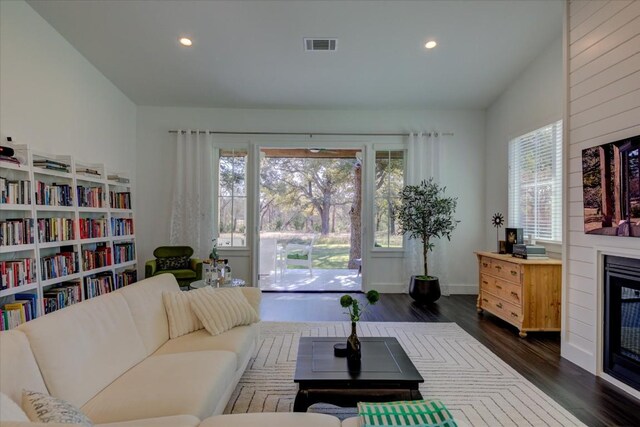 living room with dark hardwood / wood-style flooring, a wealth of natural light, a large fireplace, and vaulted ceiling