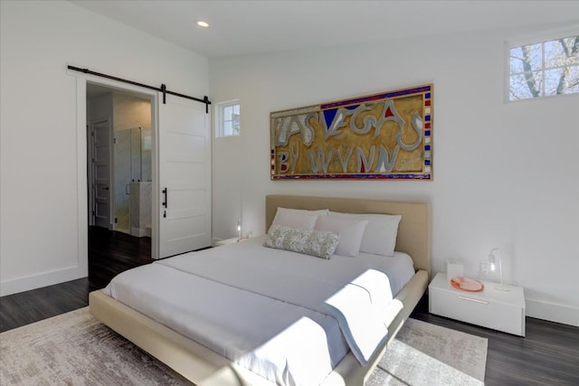 bedroom featuring connected bathroom, a barn door, dark hardwood / wood-style flooring, and vaulted ceiling