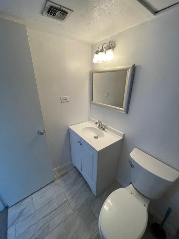 bathroom with vanity, toilet, and a textured ceiling