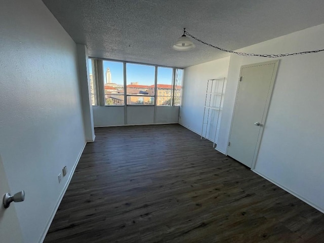 empty room with dark hardwood / wood-style flooring and a textured ceiling