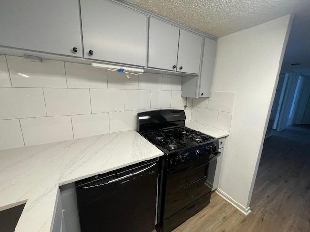 kitchen with tasteful backsplash, light stone countertops, light hardwood / wood-style flooring, and black appliances