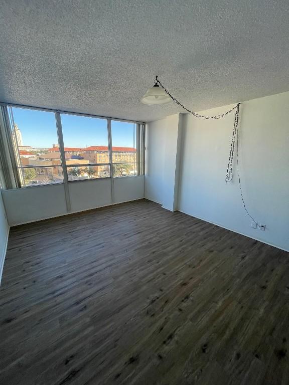 spare room featuring dark hardwood / wood-style floors and a textured ceiling