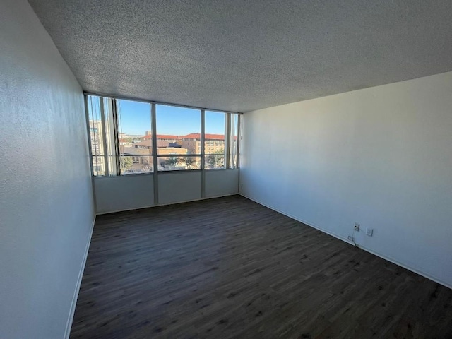 empty room featuring dark wood-type flooring and a textured ceiling