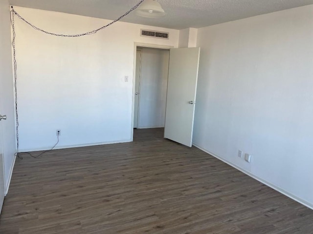 empty room with dark hardwood / wood-style floors and a textured ceiling