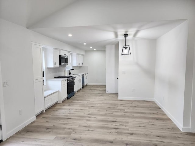 kitchen featuring sink, light hardwood / wood-style flooring, hanging light fixtures, stainless steel appliances, and white cabinets