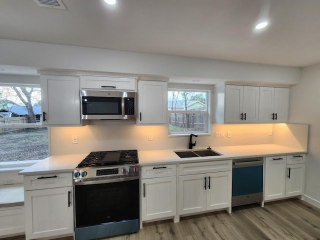 kitchen featuring stainless steel appliances, a healthy amount of sunlight, sink, and white cabinets