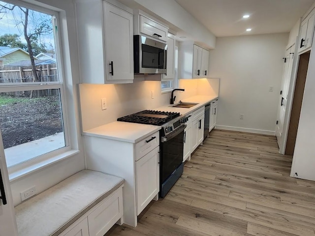 kitchen featuring a healthy amount of sunlight, appliances with stainless steel finishes, sink, and white cabinets