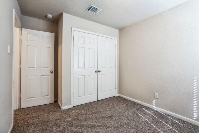 unfurnished bedroom featuring a closet and dark colored carpet