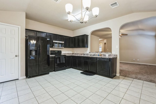 kitchen featuring hanging light fixtures, light tile patterned flooring, light stone counters, and black appliances