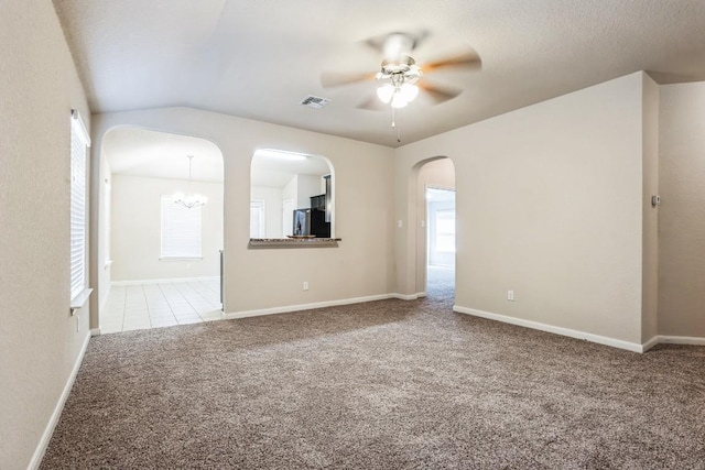 carpeted empty room featuring vaulted ceiling and ceiling fan with notable chandelier