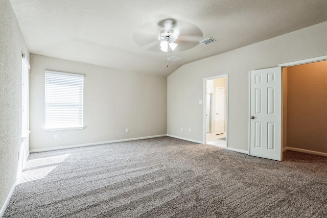 unfurnished bedroom featuring vaulted ceiling, ensuite bathroom, light colored carpet, ceiling fan, and a textured ceiling