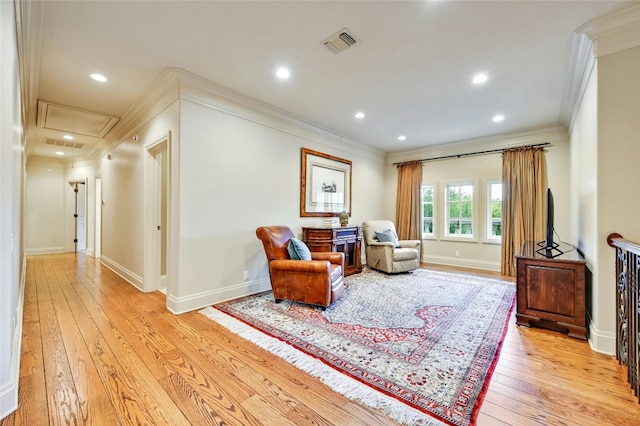 sitting room with crown molding and light hardwood / wood-style flooring