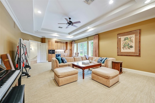 carpeted living room with a tray ceiling, ornamental molding, and ceiling fan