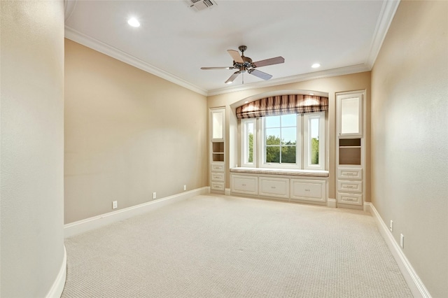 empty room featuring crown molding, light colored carpet, and ceiling fan