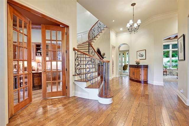 entryway featuring an inviting chandelier, hardwood / wood-style floors, crown molding, and a healthy amount of sunlight