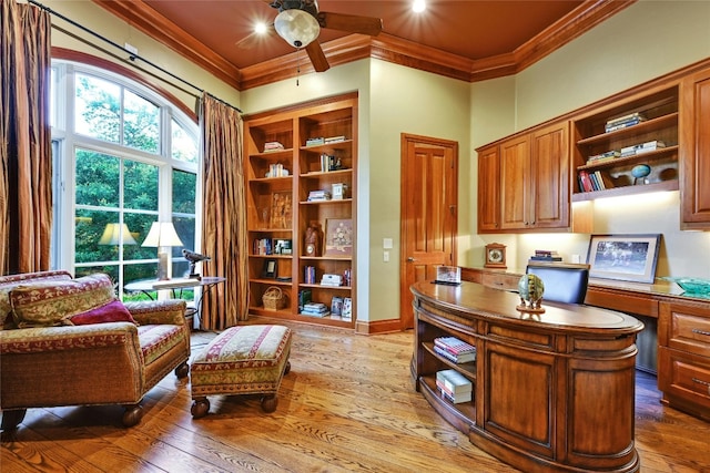 office featuring crown molding, ceiling fan, built in desk, and hardwood / wood-style floors