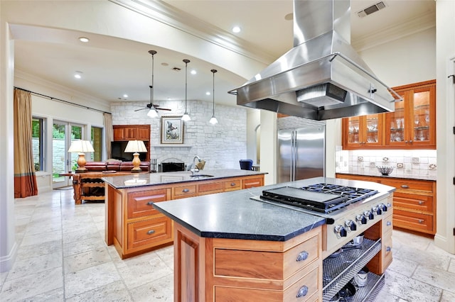 kitchen featuring pendant lighting, built in refrigerator, a center island, island exhaust hood, and a stone fireplace