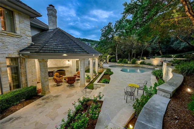 view of pool with exterior fireplace, a gazebo, and a patio area