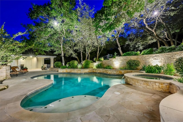 pool at twilight with a patio area and an in ground hot tub