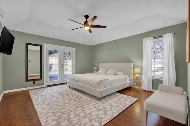 bedroom featuring hardwood / wood-style flooring, a raised ceiling, access to exterior, and ceiling fan