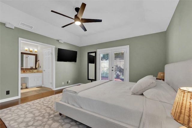 bedroom with french doors, connected bathroom, a raised ceiling, ceiling fan, and light hardwood / wood-style floors