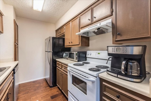 kitchen featuring appliances with stainless steel finishes, light countertops, dark wood finished floors, and under cabinet range hood