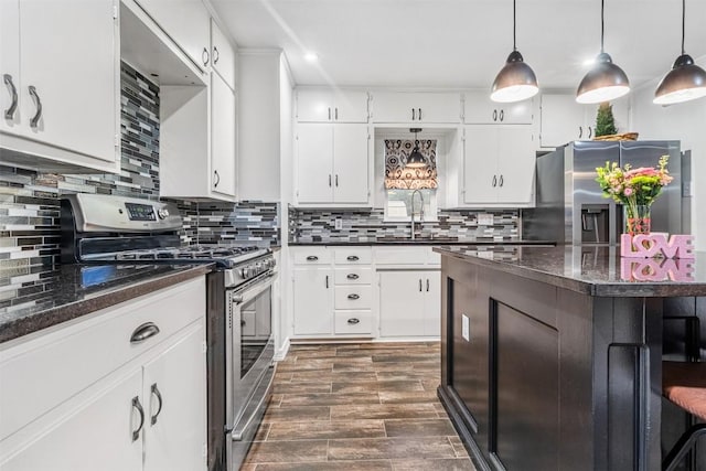 kitchen featuring stainless steel appliances, sink, pendant lighting, and white cabinets