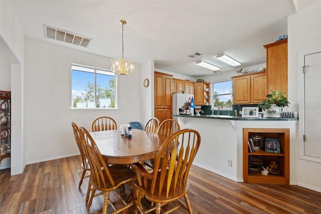 dining space with dark wood-type flooring and a notable chandelier