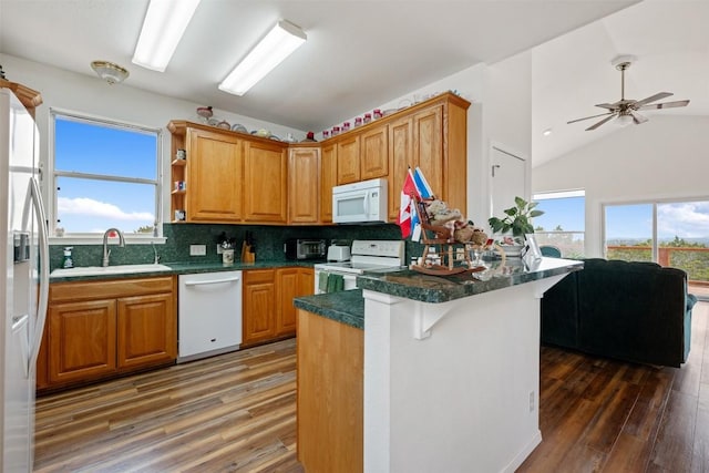 kitchen with lofted ceiling, sink, a kitchen breakfast bar, dark hardwood / wood-style flooring, and white appliances